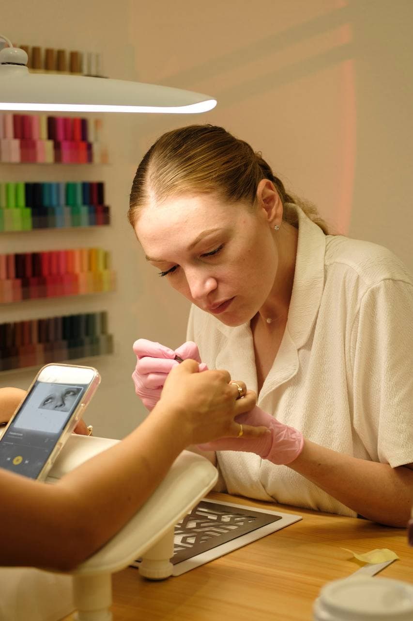 Polina at her nail workstation surrounded by a wall of nail polishes in every color