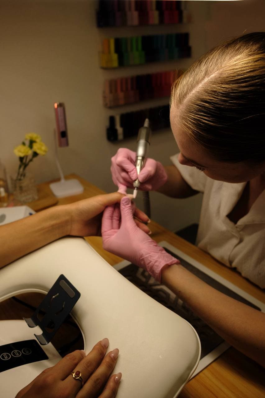 Polina refining a nail edge with the drill at her station