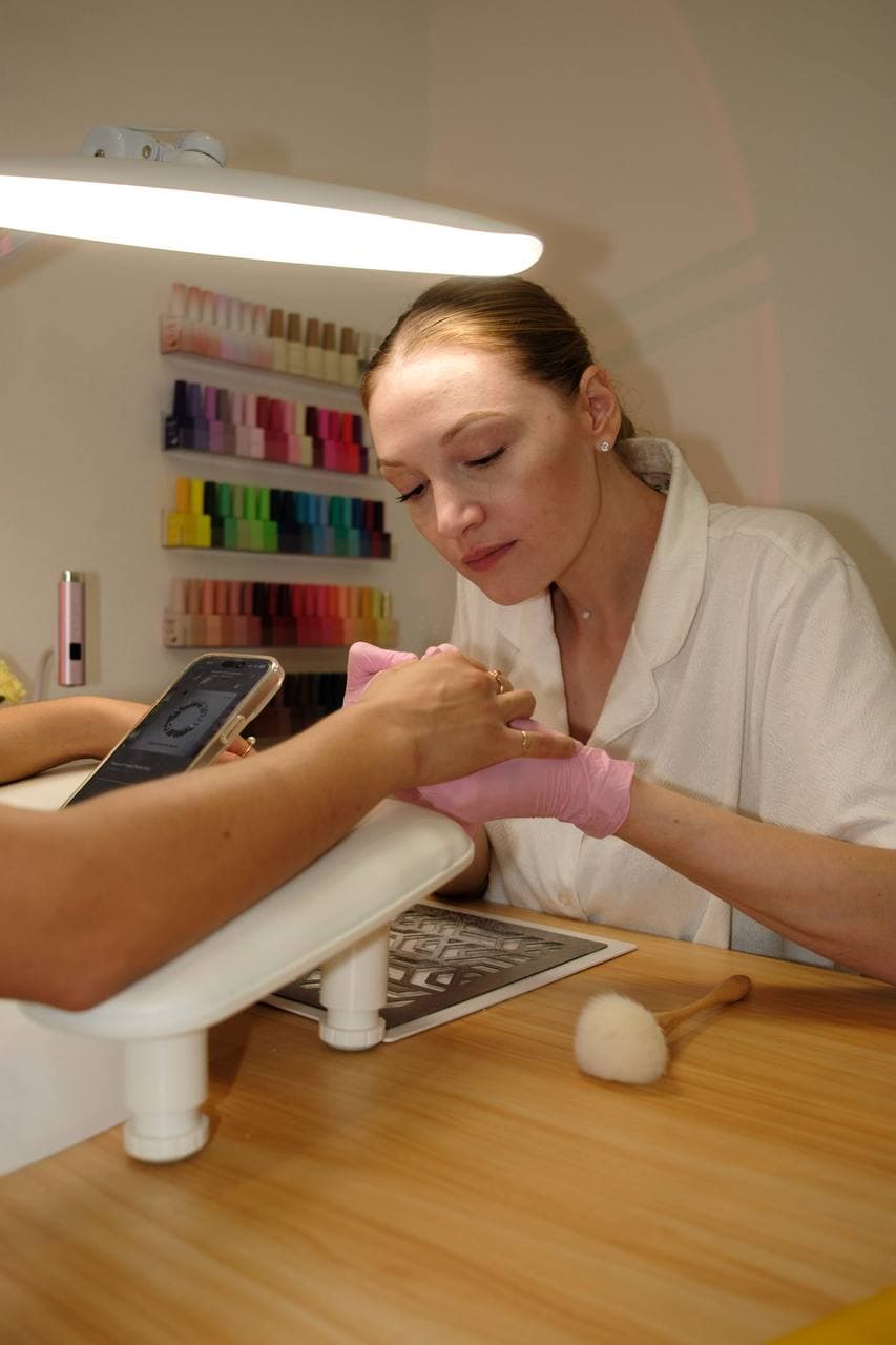 Polina working attentively with a client's hand on the cushion